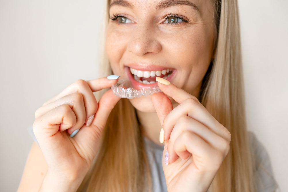 Young woman holding invisible aligner. Dental health, beautiful smile